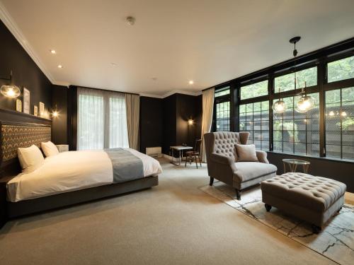 a bedroom with a bed and a chair at LONGINGHOUSE Kyukaruizawa Suwanomori in Karuizawa