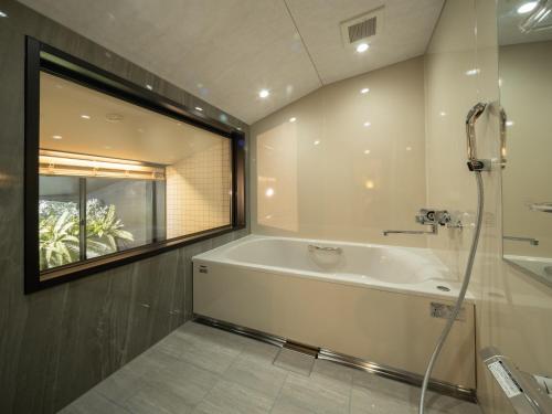 a bathroom with a bath tub and a window at LONGINGHOUSE Kyukaruizawa Suwanomori in Karuizawa