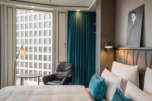 a hotel room with a bed and a chair and a window at Motel One Berlin-Upper West in Berlin