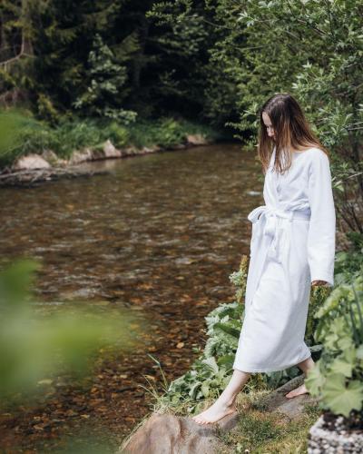a woman in a white dress standing on a rock by a river at Guesthouse St Nikolaus in Ultimo