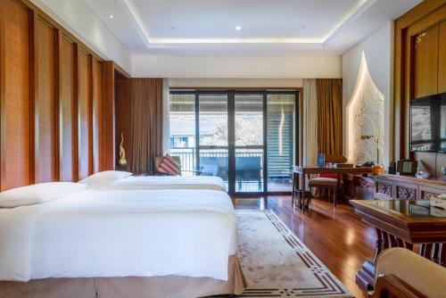 a hotel room with two beds and a desk at InterContinental Xishuangbanna Resort by IHG in Jinghong