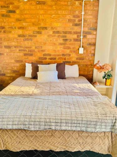 Un dormitorio con una cama con una pared de ladrillos. en Serenity haven in Johannesburg, en Johannesburgo