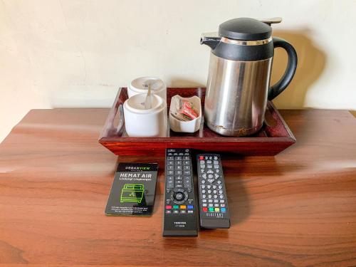 a tray with remote controls and a coffee pot on a table at Urbanview Sasono Putro Condoongcatur by RedDoorz in Yogyakarta