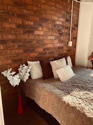 1 dormitorio con pared de ladrillo y cama con almohadas en Serenity haven in Johannesburg, en Johannesburgo