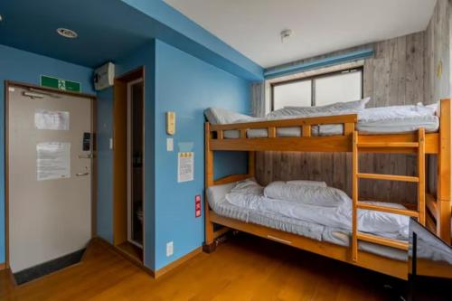 two bunk beds in a room with a blue wall at イーストコート長崎 in Tokyo