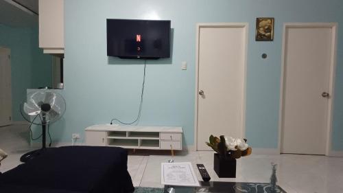 a living room with a couch and a tv on a wall at Jens Samal Vacation Rental - Centrally Located - Fully Furnished 2br WIFI in Babak