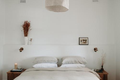 um quarto branco com uma cama com 2 almofadas em The Settler - Boutique cottage em Dubbo