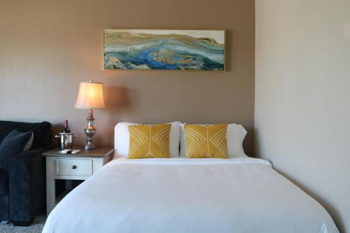 a bedroom with a white bed and a table with a lamp at Bellanca in Discovery Bay