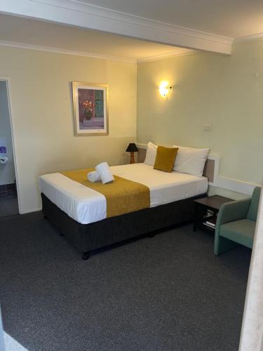 a hotel room with a large bed and a chair at Biloela Centre Motel & Steakhouse Restaurant in Biloela