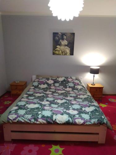 1 dormitorio con 1 cama con edredón de flores en Biały Domek, noclegi Gołdap, en Gołdap