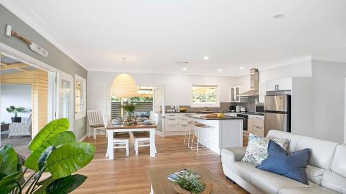 a white living room with a couch and a kitchen at River Shack in Shoalhaven Heads