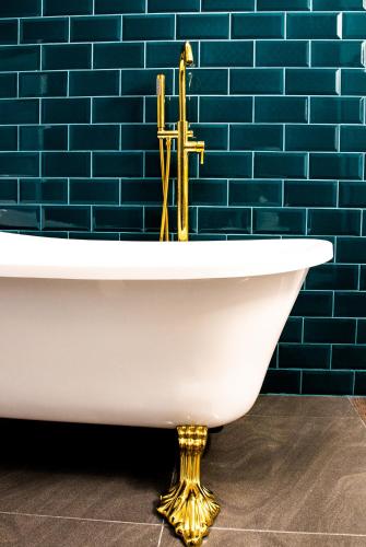 a white bath tub with a gold faucet in a bathroom at Apartament Pasaż in Giżycko
