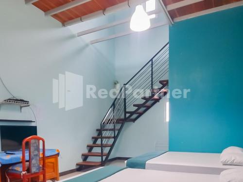 a bedroom with a blue wall and a staircase at Syariah Safar Guest House Mitra RedDoorz in Cijoho