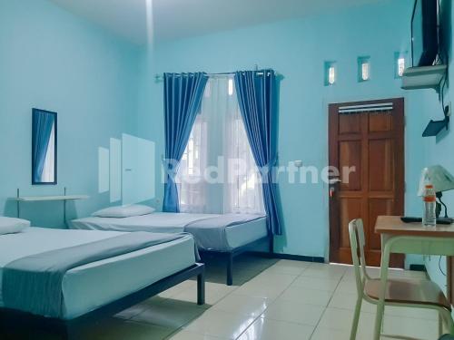 a blue room with two beds and a table at Syariah Safar Guest House Mitra RedDoorz in Cijoho
