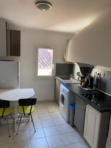 une cuisine avec un lave-linge, une table et des chaises dans l'établissement La Ciotat T2 à proximité du port, à La Ciotat