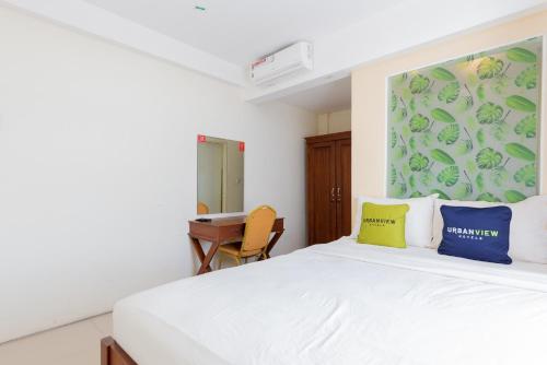 a bedroom with a white bed with blue and yellow pillows at Urbanview Erga Family Residence Syariah Surabaya in Surabaya