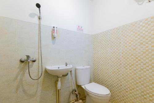 a bathroom with a shower and a toilet and a sink at Urbanview Erga Family Residence Syariah Surabaya in Surabaya