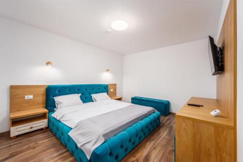 una camera con letto blu e televisore di Ellys Residence a Voroneţ