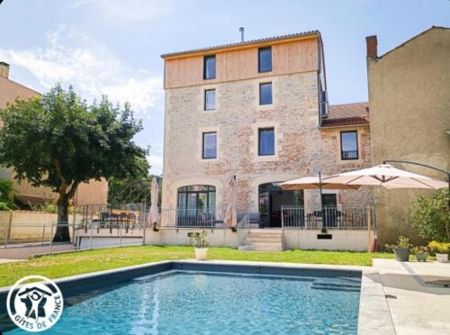 a house with a swimming pool in front of a building at La Bellours Chambre D'Hôtes in Cahors