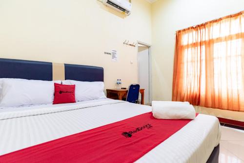 a bedroom with a large bed with red pillows on it at RedDoorz near Kelapa Gading in Jakarta