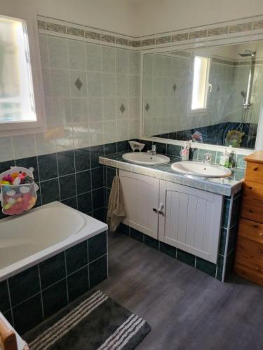une salle de bain avec deux lavabos, une baignoire et un miroir dans l'établissement Location maison avec piscine, à Grasse