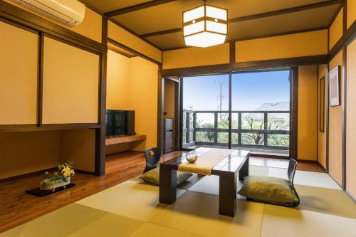een woonkamer met een tafel en een groot raam bij 料理の宿　伊豆の花 in Ito