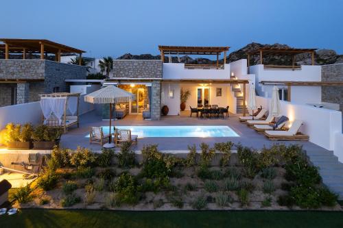 a villa with a swimming pool at night at OLIVES seaside villas (4elies) in Plaka