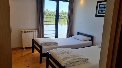 two beds in a room with a view of the water at B&B Botel Charlie in Belgrade