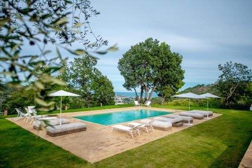 una piscina con sedie a sdraio e ombrelloni di A Casa Da Angelo - Country House PrivatePool & AirCO a Grottammare