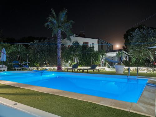 una grande piscina blu in un cortile di notte di La casa di Gioggiò a Ioppolo Giancaxio
