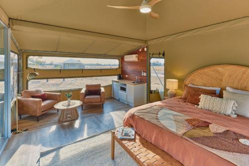 Willow Wood Glamping Retreat في Broadwater: غرفة نوم مع سرير وغرفة معيشة