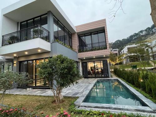 a house with a swimming pool in front of it at Villa D’Helen Venus Flamingo Đại Lải in Yen