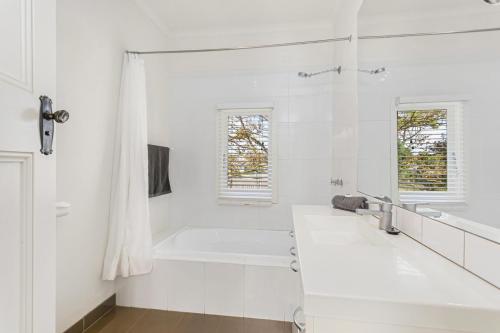 Baño blanco con bañera y lavamanos en Sorrento Beach House - Perfect spot and NEW pool, en Sorrento