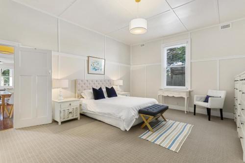 a white bedroom with a bed and a chair at Sorrento Beach House - Perfect spot and NEW pool in Sorrento