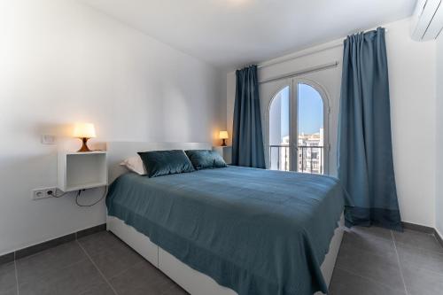 a bedroom with a bed and a window with blue curtains at 210 Mijas Sea View Bahia Playa in La Cala de Mijas