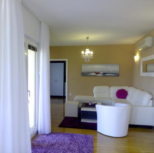 a living room with white furniture and a chandelier at Villa Jelena in Zadar