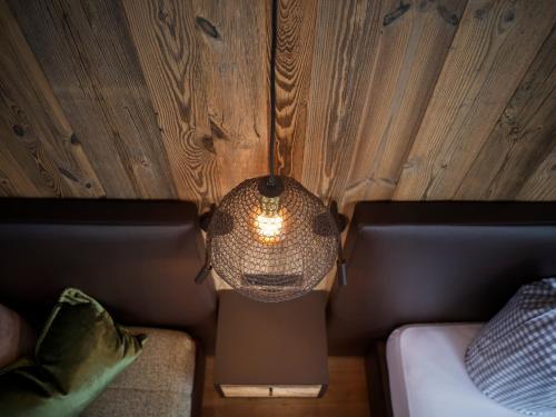 a lamp hanging from a wooden wall next to a couch at Haus Barbara in Alpbach