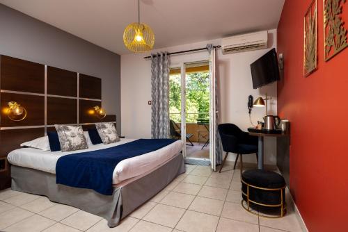 a bedroom with a bed and a desk and a window at The Originals City, Hôtel Côté Sud, Marseille Est in Allauch