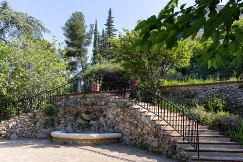 a set of stairs with a stone wall and a bench at The Originals City, Hôtel Côté Sud, Marseille Est in Allauch