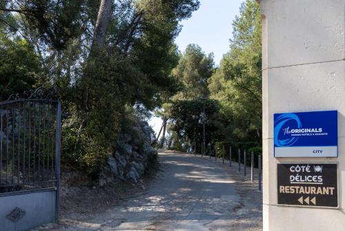 a sign on the side of a building next to a road at The Originals City, Hôtel Côté Sud, Marseille Est in Allauch