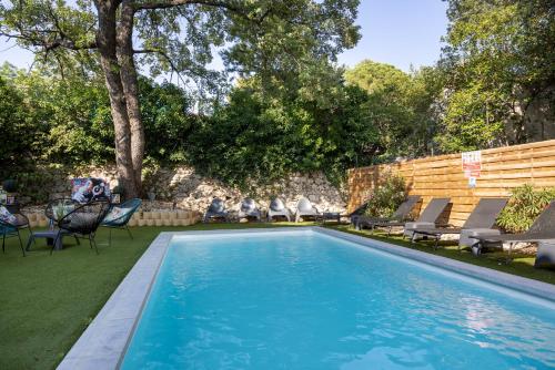 a swimming pool with chaise lounges and chairs in a backyard at The Originals City, Hôtel Côté Sud, Marseille Est (Inter-Hotel) in Allauch
