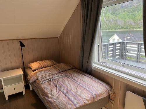 a small bedroom with a bed and a window at Old fisherman's house with 4 bedroom in Gryllefjord