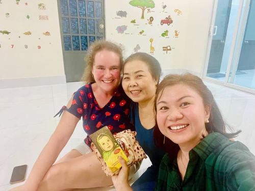 three women posing for a picture while holding books at Charis Home- Tay Ninh in Tây Ninh