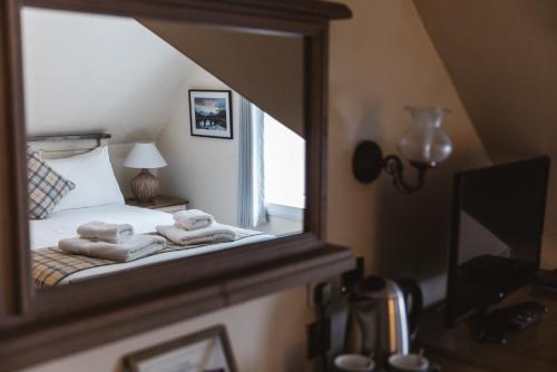 a mirror with towels on a bed in a bedroom at Greshornish House Hotel in Edinbane
