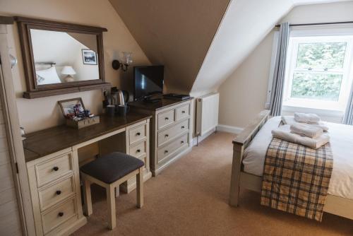 a bedroom with a desk with a mirror and a bed at Greshornish House Hotel in Edinbane