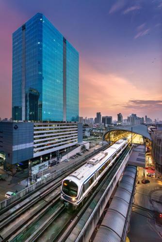 a train on tracks in a city with buildings at Nasa Bangkok in Bangkok