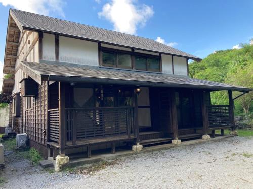una casa de madera con techo de gambrel en ＰＥＮＳＩＯＮ　ＳＨＩＭＡＫＡＺＥ en Motobu