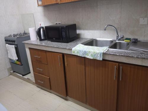 una cucina con lavandino e forno a microonde di Lux Suites Wawazi Court Apartments a Nairobi