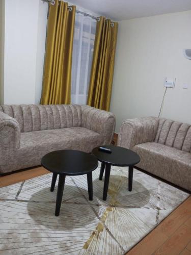 un soggiorno con divano e 2 tavoli di Lux Suites Wawazi Court Apartments a Nairobi