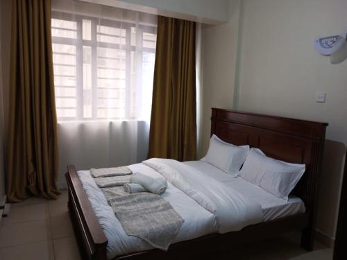 un letto con lenzuola e cuscini bianchi e una finestra di Lux Suites Wawazi Court Apartments a Nairobi